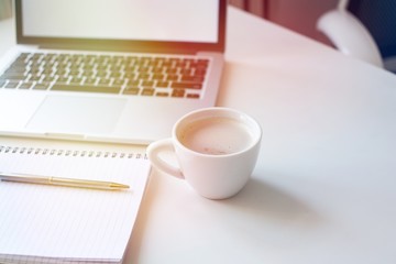 Laptop mockup on work desk in sunset. Close-up laptop, coffee, with morning light. Modern, thin laptop design.White. Isolated screen for mockup. Laptop profile. Home office