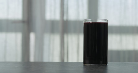 bilberry juice in glass on concrete countertop with window on background