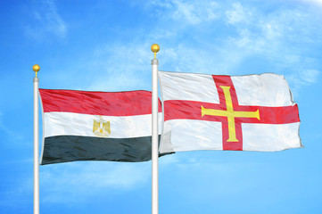 Egypt and Guernsey two flags on flagpoles and blue cloudy sky