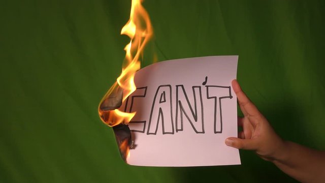 A hand holds the burning paper with I can't cant text word on it.