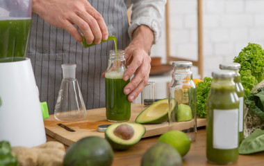 Healthy man enjoys making green vegetables detox cleanse
