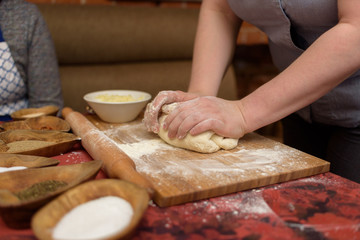 Female hands knead the dough.