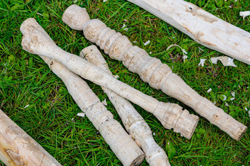 Turned wooden poles lying on grass with wood shavings