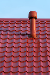 Pipe of a modern ventilation system on the roof of the house with metal tiles