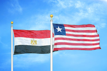 Egypt and Liberia two flags on flagpoles and blue cloudy sky