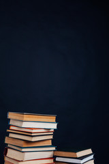 many stacks of educational books for learning preparation for college exams on a black background
