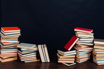 many stacks of educational books for learning preparation for college exams on a black background