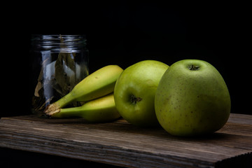 bananas and green apples on black background