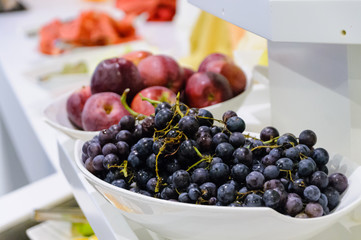 Grapes, apples, and melon in white bowls in a hotel.