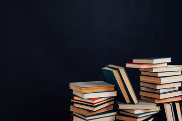 many stacks of educational books for learning preparation for college exams on a black background