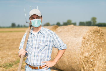 Farmer in his field while wearing a mask, coronavirus pandemic concept