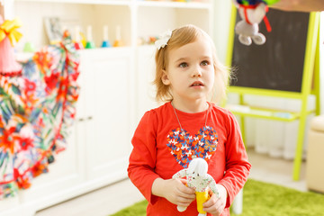 little girl blonde plays with toy puppet theatre.
