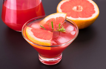 
Grapefruit cocktail in a glass with ice cubes on a black background. Copy space. Top view.