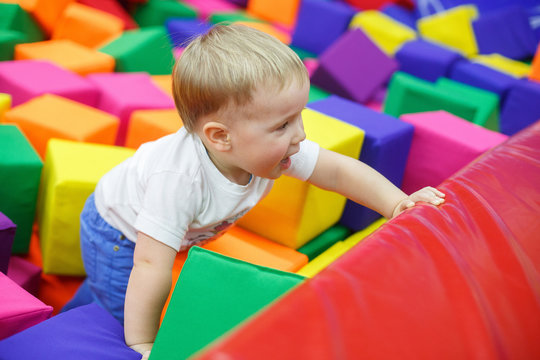 miling child in playroom. funny baby boy in a pool with colorful soft toy cubes. family rest in the children's center. portrait a little boy have fun in playing room close up. happy childhood concept