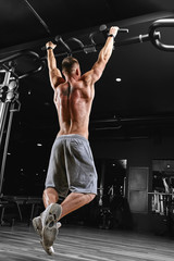 Fototapeta na wymiar Strong man doing pull-ups on a bar in a gym.