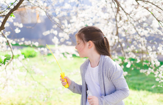  girl, white t-shirt and gray jacket, flowering trees, soap bubbles