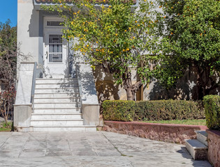 yard with trees and marble stairs to vintage house entrance white door