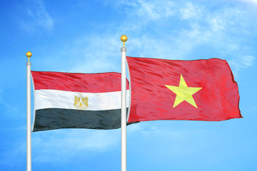 Egypt and Vietnam two flags on flagpoles and blue cloudy sky