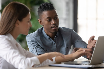 Confident african american businessman talking with businesswoman using laptop for presentation in...