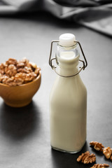 Vegan milk from walnuts on dark background, alternative plant based milk.