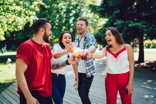 Excited friends clinking cups with drinks