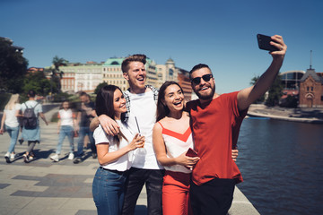 Excited friends posing for selfie on embankment