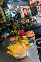 A chicken carcase with a red rose stuck down its throat on a table outside a restaurant in Hanoi, Vietnam