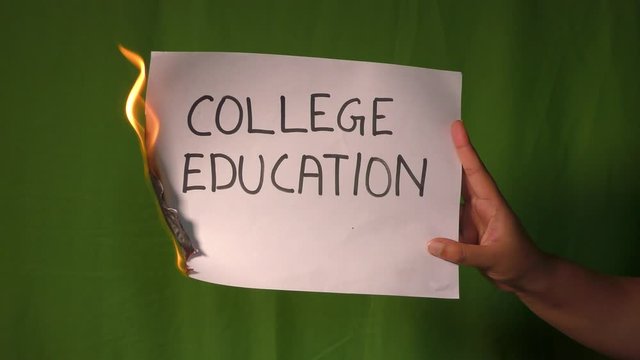 A hand holds the burning paper with college education text word on it.