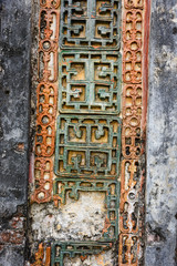 Old, damaged ceramic relief work on the column wall of a Chinese style building.