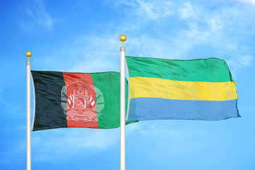 Afghanistan and Gabon  two flags on flagpoles and blue cloudy sky