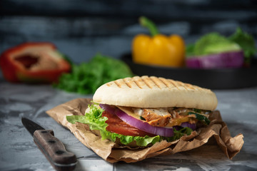 freshly cooked grilled sandwich on parchment paper close-up, rustic style wooden background
