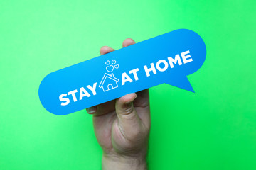 Hand holding speech bubble with stay at home.