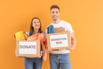 Volunteers with donations for orphans on color background