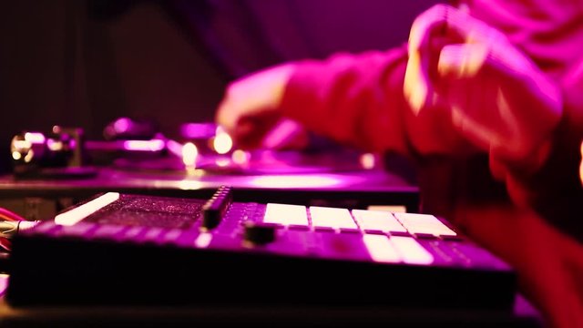 Hip hop beatmaker & disc jockey playing on concert stage.Professional beat maker plays beats with drum machine on party in night club in bright magenta lights