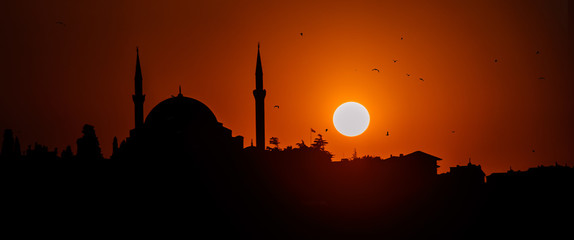 Panoramic silhouette of islam religion mosque at sun sunset twilight