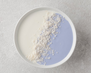 Smoothies in a bowl with yogurt, coconut and blue matcha tea, top view.