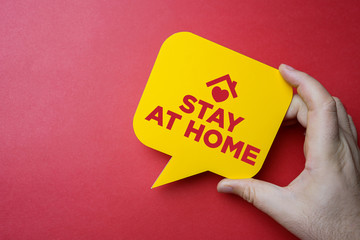 Hand holding speech bubble with stay at home.
