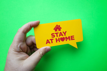 Hand holding speech bubble with stay at home.