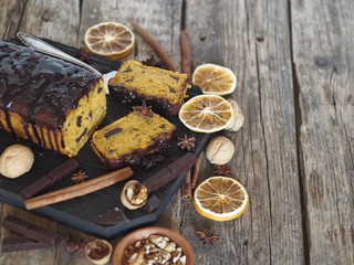 Fototapeta premium Festive chocolate soft pumpkin muffin, poured with chocolate icing, on a wooden ancient background.