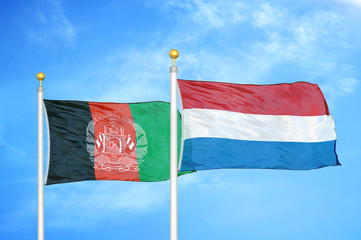 Afghanistan and Netherlands  two flags on flagpoles and blue cloudy sky