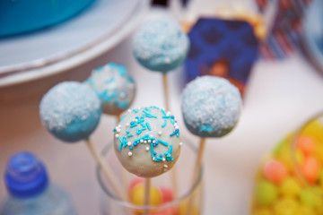 Concept sweet couple in love for your design. You can draw faces, emotions. Stick man. White chocolate cake pops decorated with blue confectionery sprinkles on a blue background.