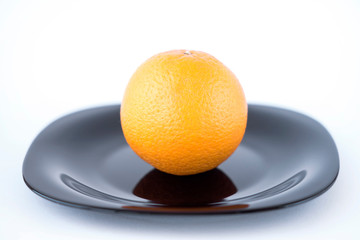 Juicy tasty orange on black plate on white background isolated