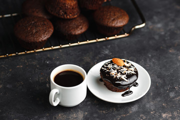 Chocolate cupcakes, muffins with banana, nuts and a Cup of coffee. On a black table and a dark background. Top view, side view. Close-up and medium plan. Space for text.