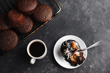 Chocolate cupcakes, muffins with banana, nuts and a Cup of coffee. On a black table and a dark background. Top view, side view. Close-up and medium plan. Space for text.