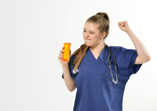 Beautiful young female medical professional with stethoscope smiling as she holds a bottle of pills rocking out - very happy with pills - studio - no PPE present