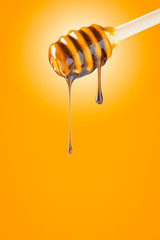 Natural honey on a wooden dipper close-up. Wooden dipper with organic honey on a yellow background.