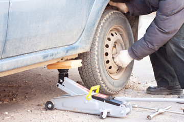 a man unscrews the bolts on the wheel of a car. wheel replacement