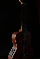 Fototapeta na wymiar Ukulele brown wood grain in dark light for playing on black background.