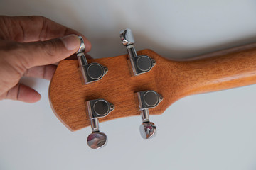 hand adjusting ukulele strings it for playing on white background.