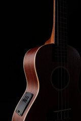 Ukulele brown wood grain in dark light for playing on black background.